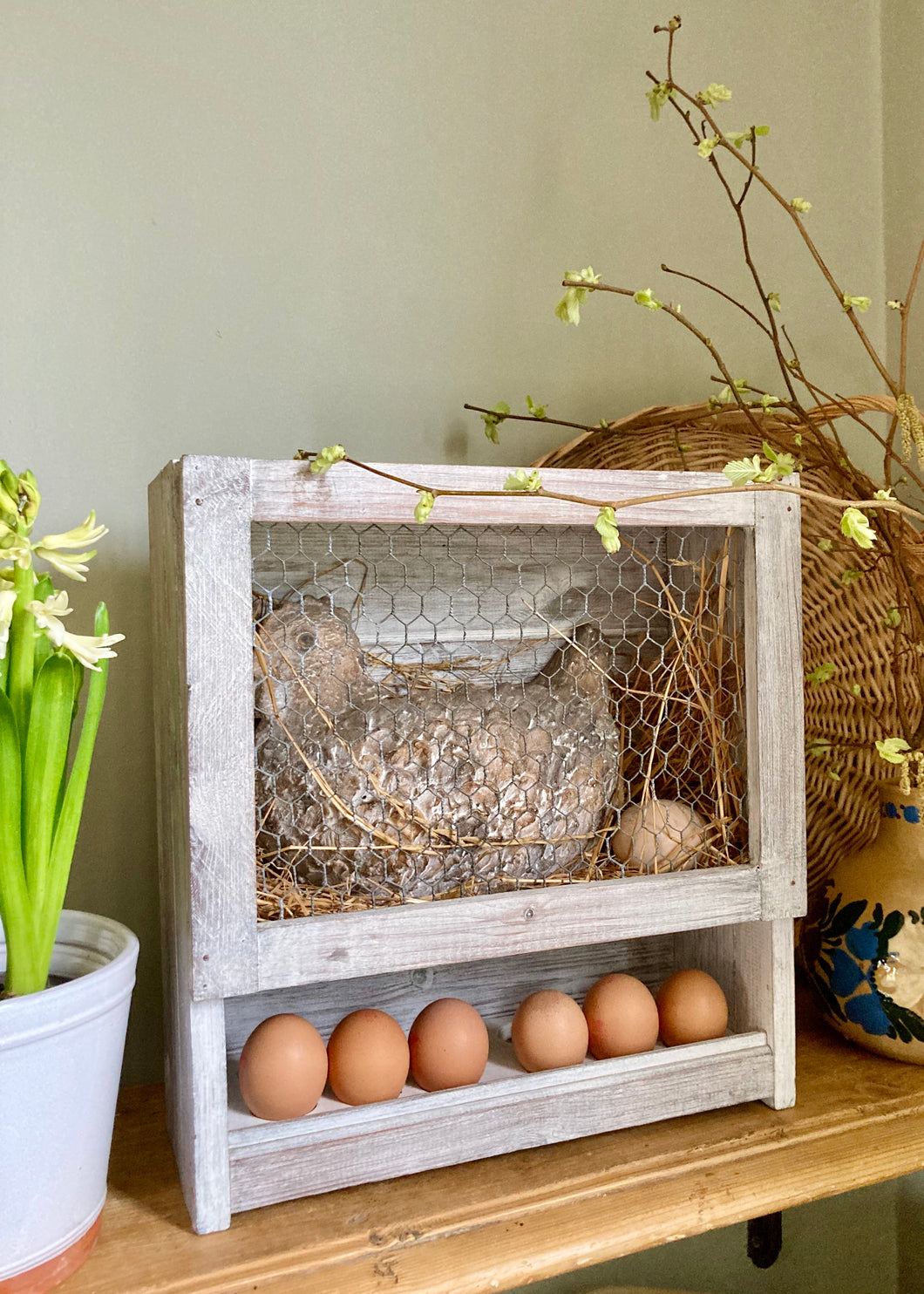 Rustic pottery chicken in nesting box with egg rack