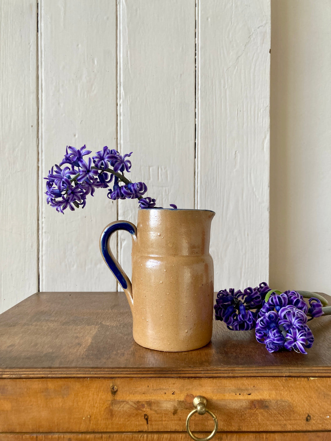 Rustic stoneware jug with blue rim/handle