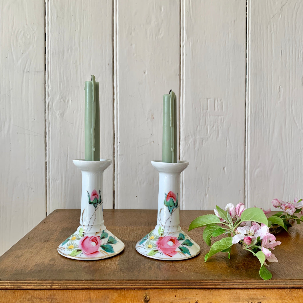 A pair of white china candlesticks hand decorated floral design