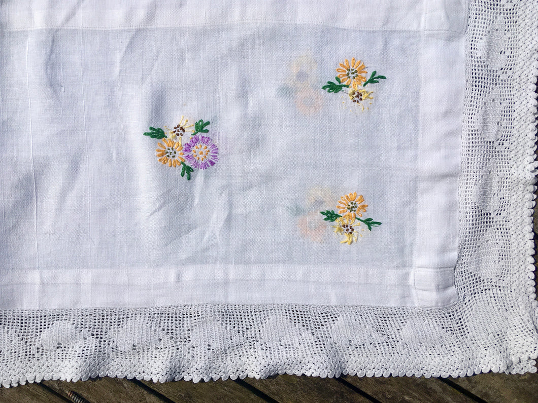 A beautifully embroidered table runner with lace edging