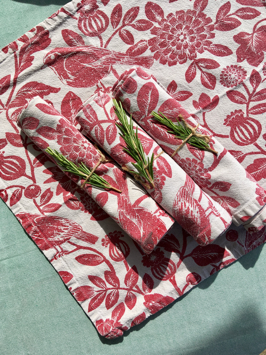 A set of four red on white printed floral napkins with plants and birds
