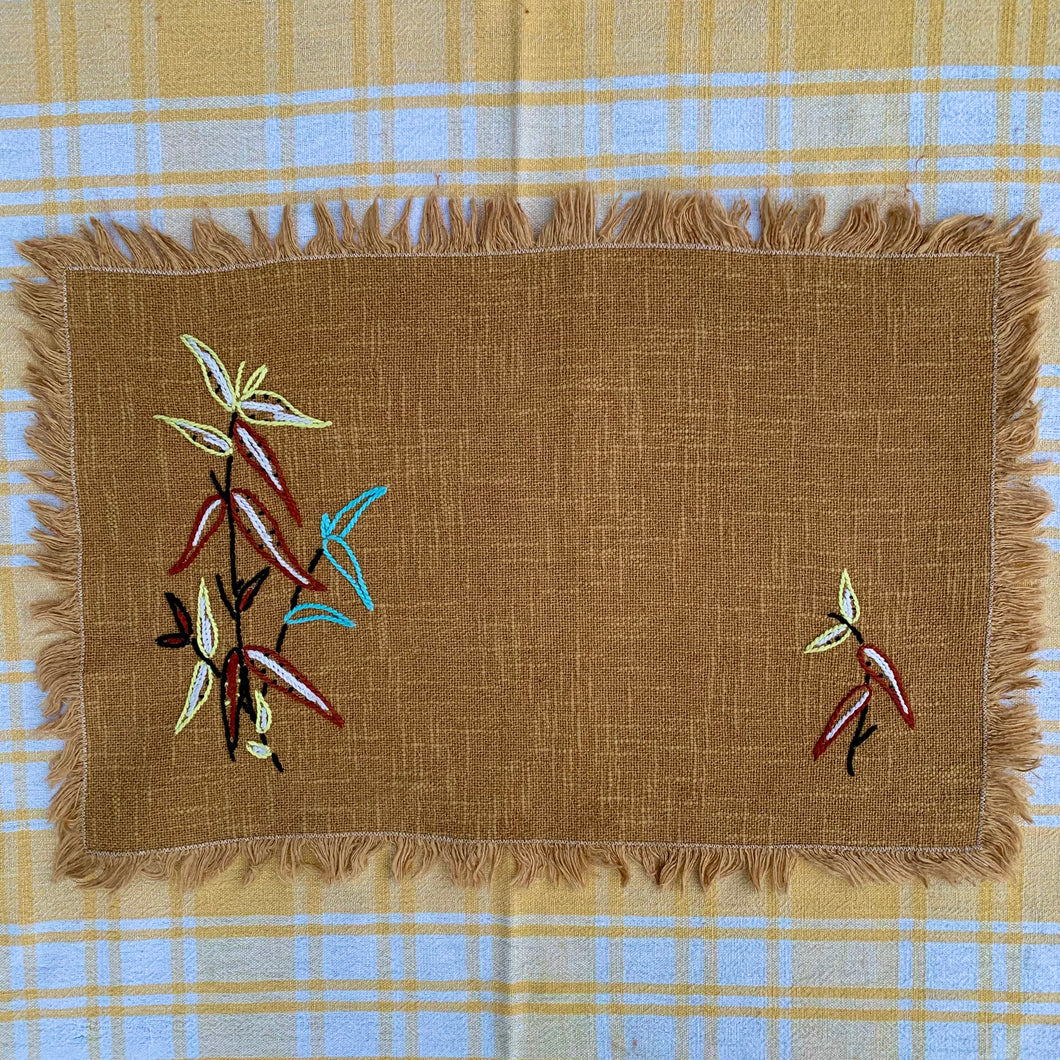 Hand embroidered, folk art style linen placemat with fringed edge.