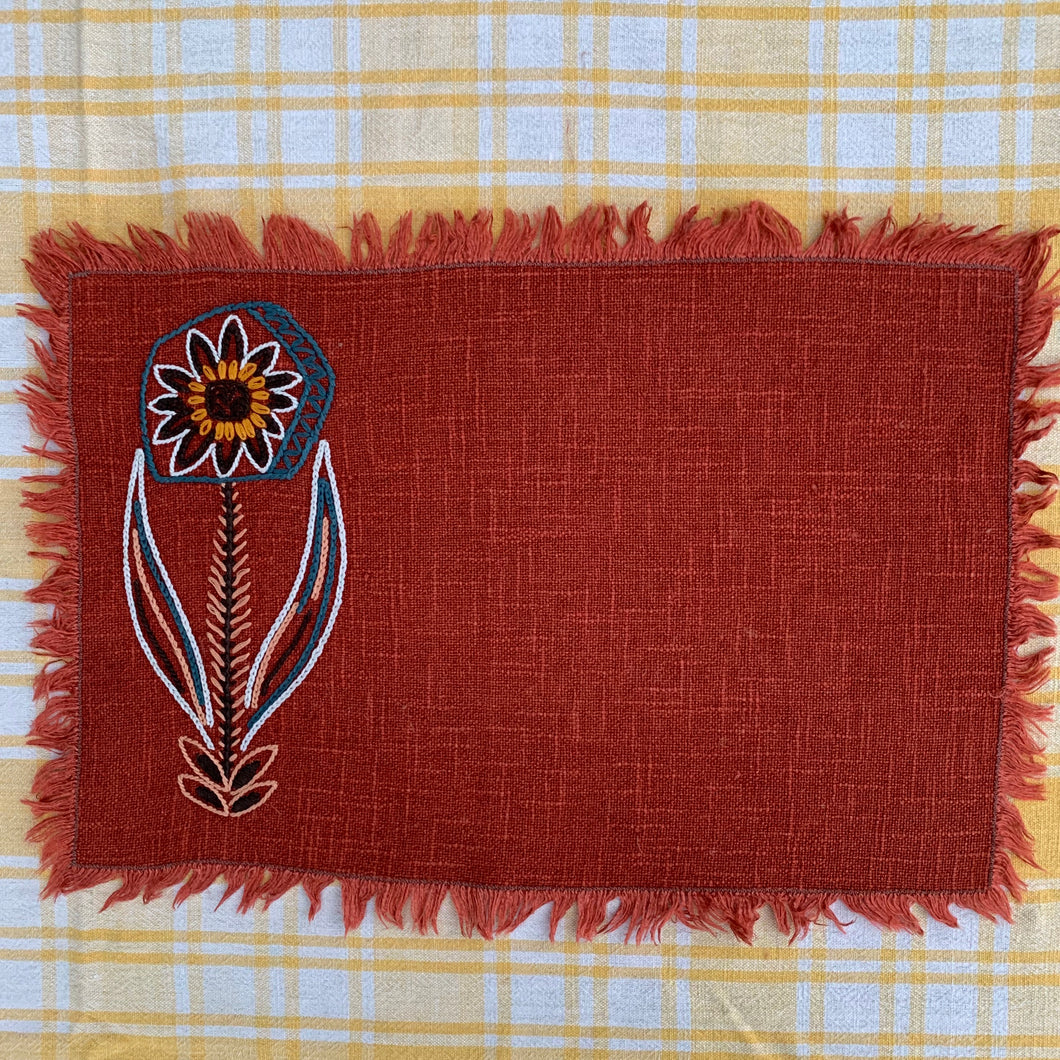 Hand embroidered, folk art style linen placemat with fringed edge.